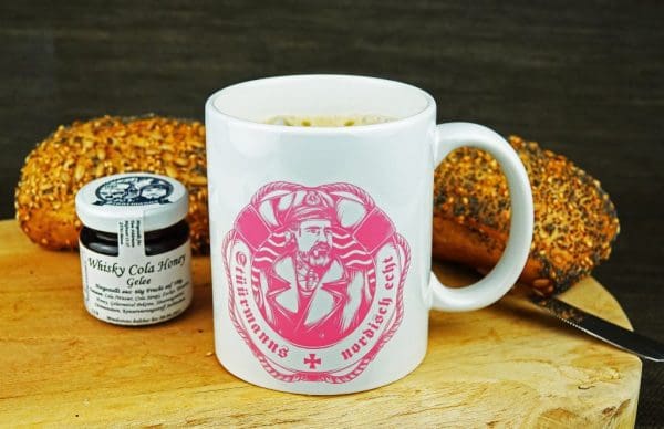 Frühstück mit Brötchen, Stüürmanns Whisky Cola Aufstrich und weiße Stüürmanns Nordisch Echt Tasse mit pinkem Stüürmanns Nordisch Echt Logo