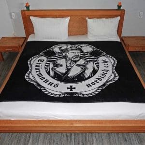 schwarze Stüürmanns Decke, Fleecedecke, Vorderseite mit großem Stüürmanns Logo auf einem Bett