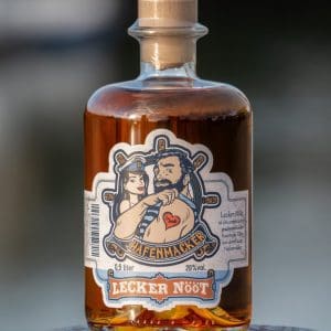 Flasche mit hellbraunen Hafenmacker Lecker Nööt Haselnusslikör mit Hafen im Hintergrund