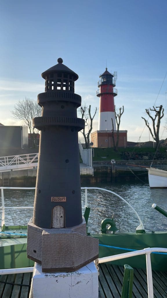 großer Nordseemerch Büsumer Leuchtturm in schwarz vor originalen Büsumer Leuchtturm im Büsumer Hafen