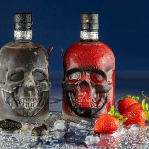 zwei Totenkopfflaschen Stüürmanns Seemannstod mit schwarzen Lakritz Likör und rotem Erdbeerc-Chili-Likör, davor Eis, Erdbeeren, Chili und Lakritzgummis