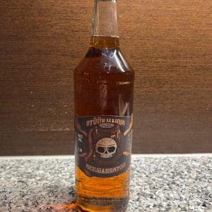 durchsichtige Flasche mit braunem Stüürmanns Seemannstod Whisky-Likör vor Holzwand